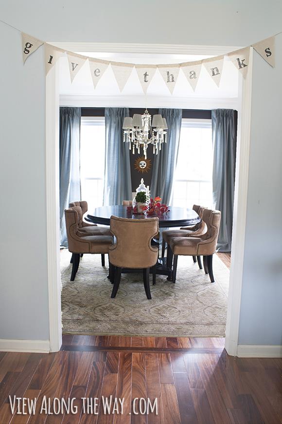 Dining Room with dark walls, upholstered chairs, crystal chandelier and teal drapes at www.viewalongtheway.com