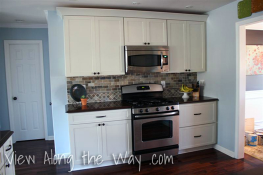 Cream Cabinet Wall in Kitchen with Stainless Appliances and Slate Backsplash