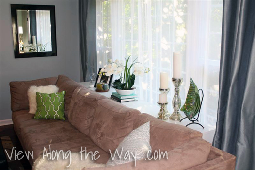 Styled/decorated sofa table behind tan sectional sofa