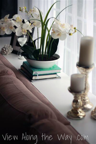 Styled/decorated sofa table behind tan sectional sofa