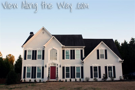 House exterior: gray with black shutters, black roof and red front door