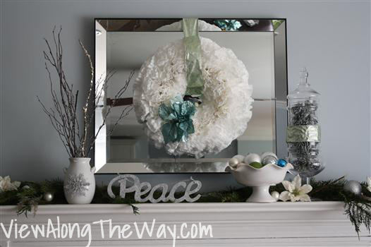Metallic-inspired holiday mantel vignette with white wreath and twigs
