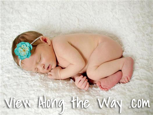 Newborn on white blanket turquoise flower