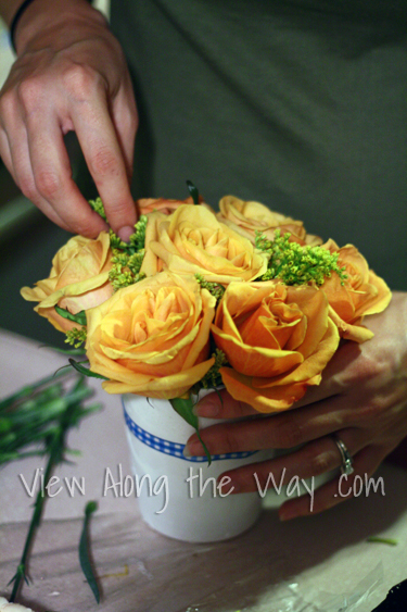 Filling a vase with roses and greenery