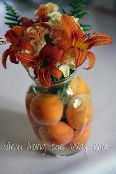 Vase with clementine oranges, lilies and carnations