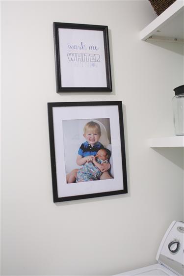 Bible verse art and child photos in a laundry room